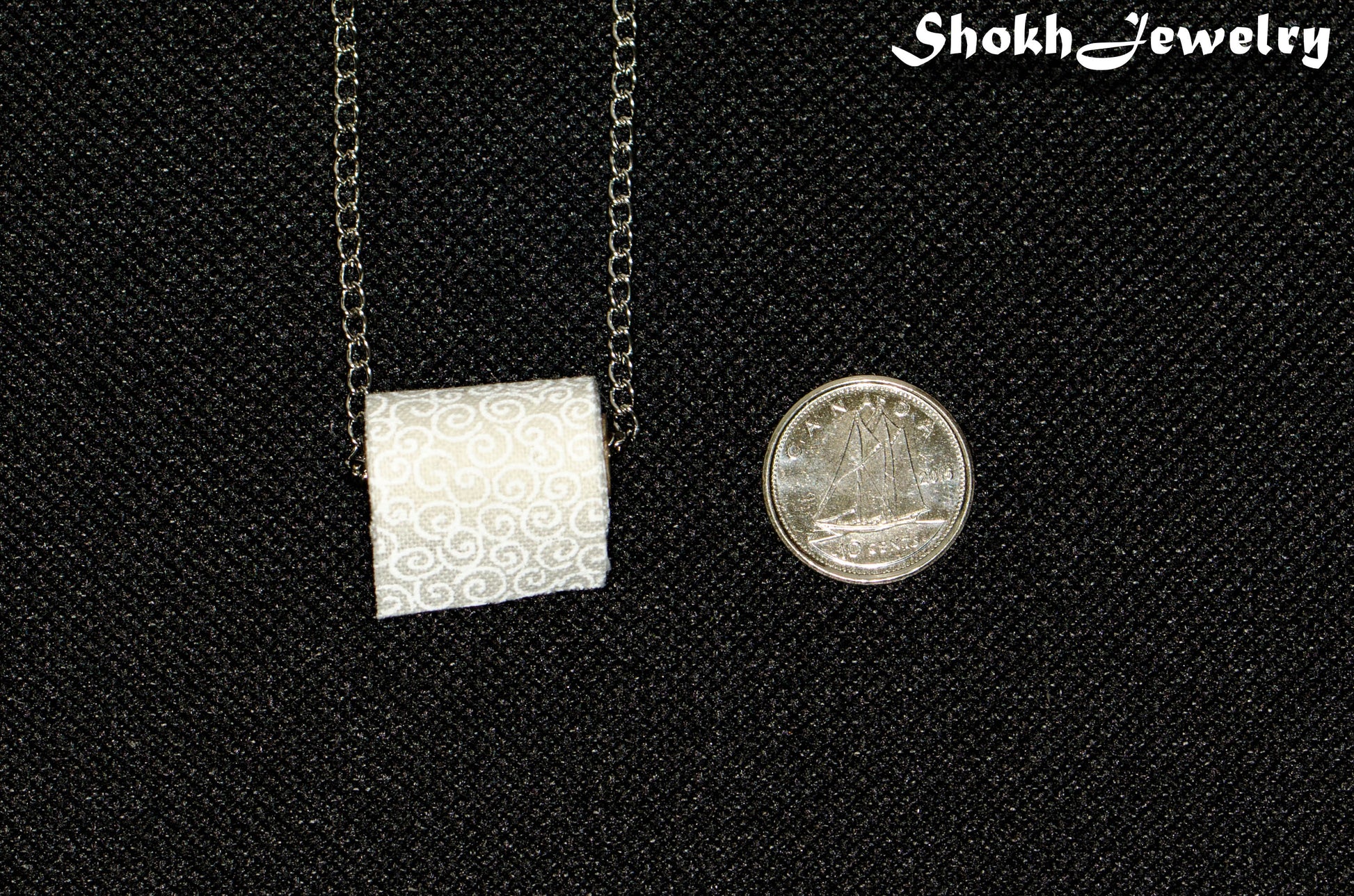 Miniature Toilet Paper Roll and Dainty Chain Choker Necklace beside a dime.