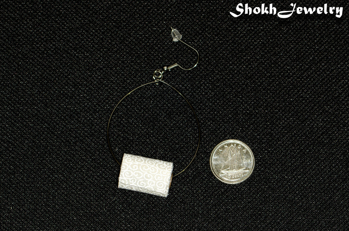 Large Miniature Toilet Paper Roll Earrings beside a dime.