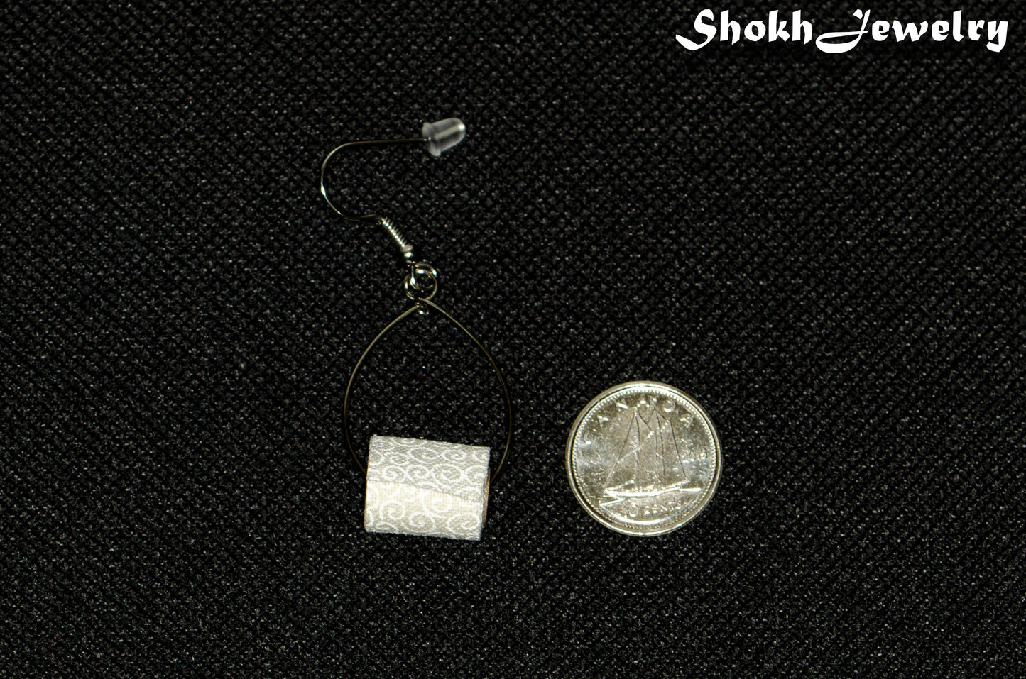 Miniature Toilet Paper Roll Earring beside a dime.