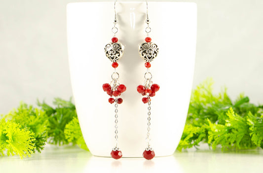 Statement Tibetan Silver Heart and Red Beaded Cluster Earrings displayed on a coffee mug.