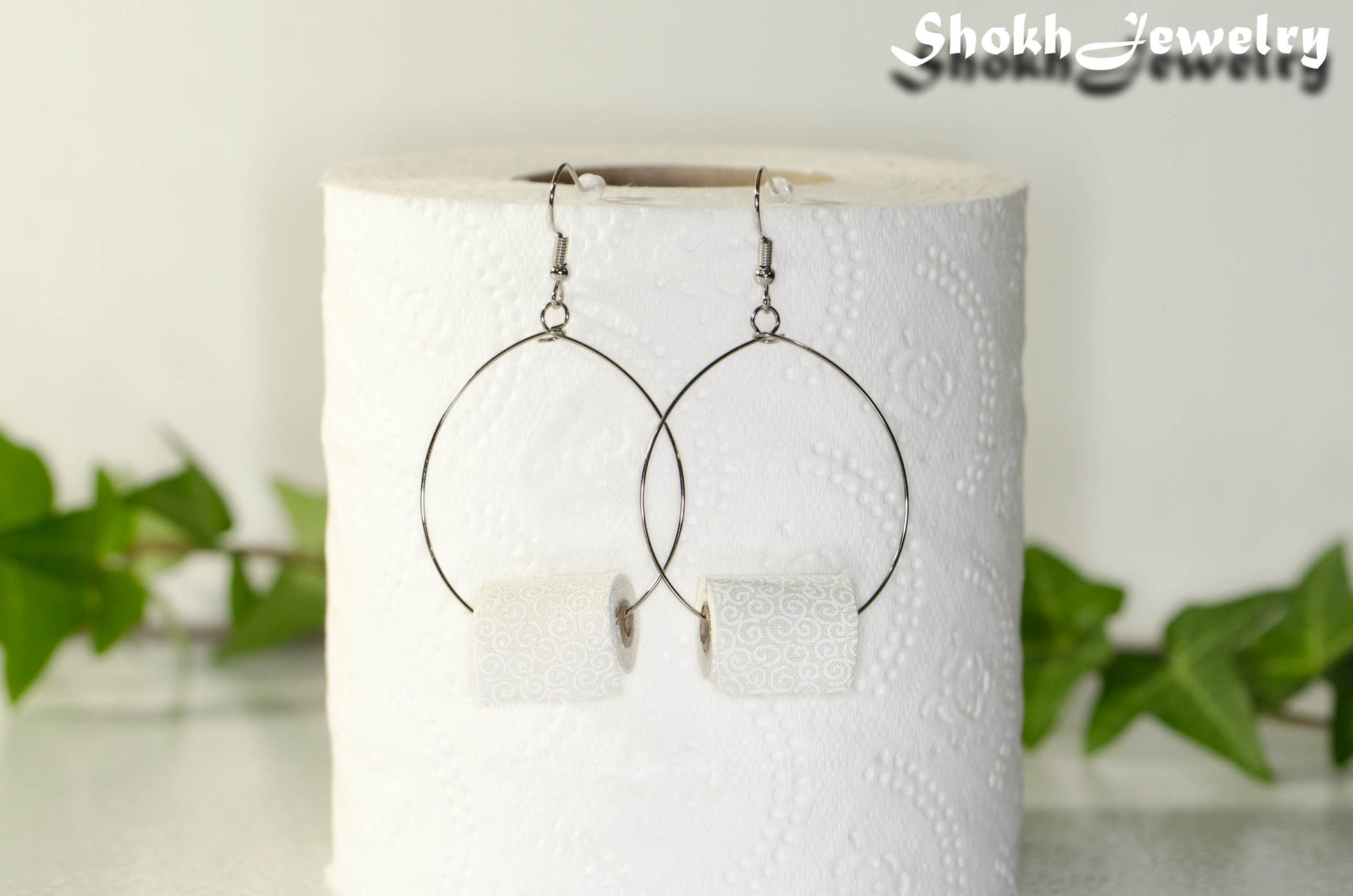 Miniature Toilet Paper Roll Earrings displayed on a toilet paper roll.