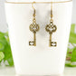 Bronze Skeleton Key Charm Earrings displayed on a tea cup.