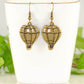 Antique Bronze Hot Air Balloon Charm Earrings displayed on a tea cup.