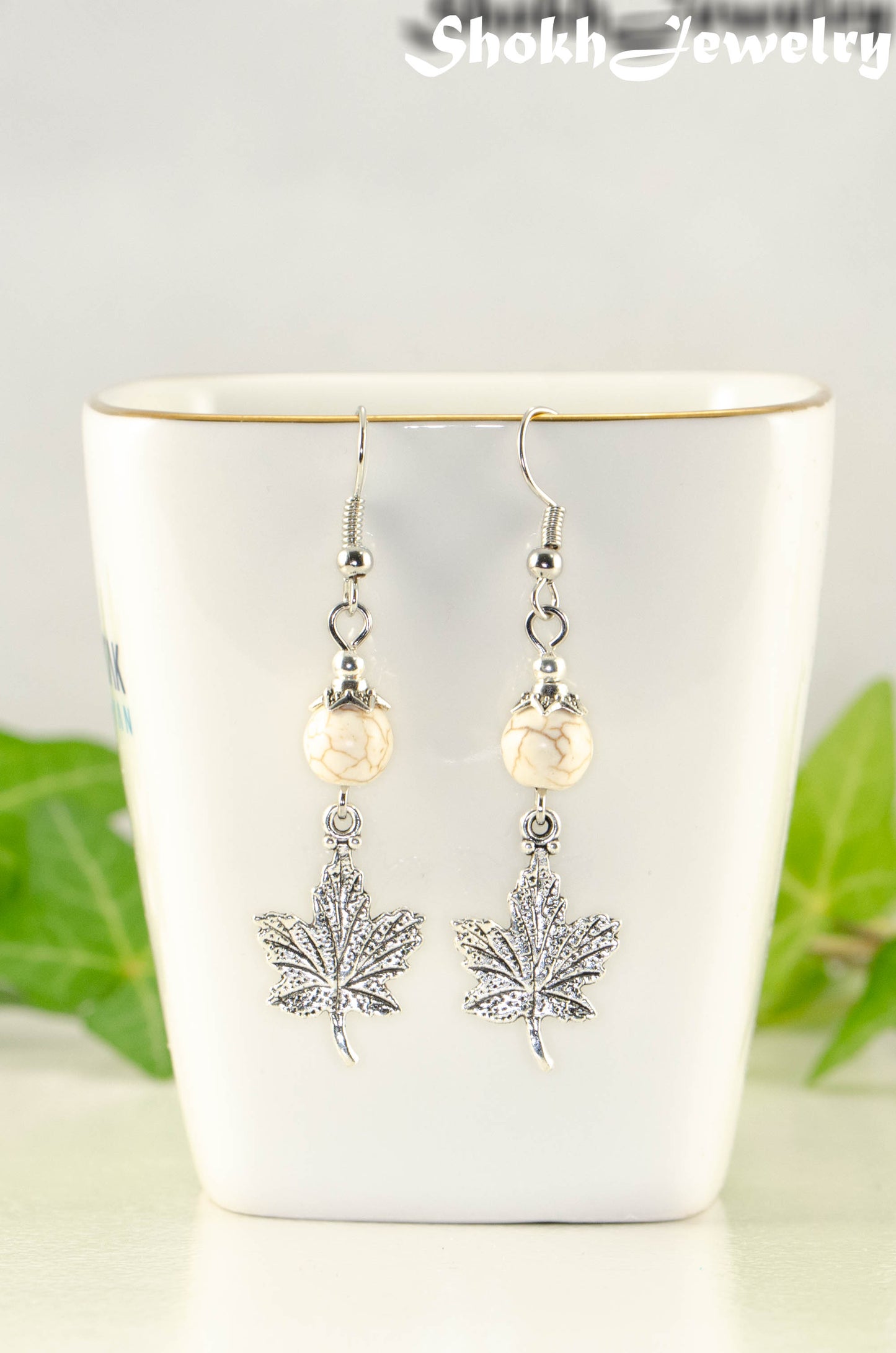 Close up of White Howlite and Tibetan Silver Maple Leaf Dangle Earrings.