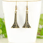 Antique Bronze 3D Eiffel Tower Charm Earrings displayed on a tea cup.