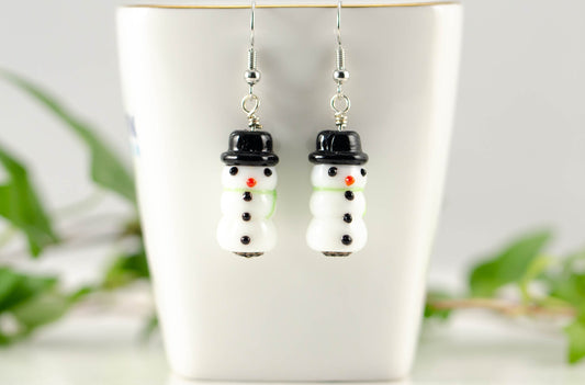 Snowman Glass Bead Earrings displayed on a tea cup.
