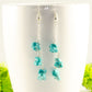 Long Silver Plated Chain and Turquoise Crystal Chip Earrings displayed on a coffee mug.