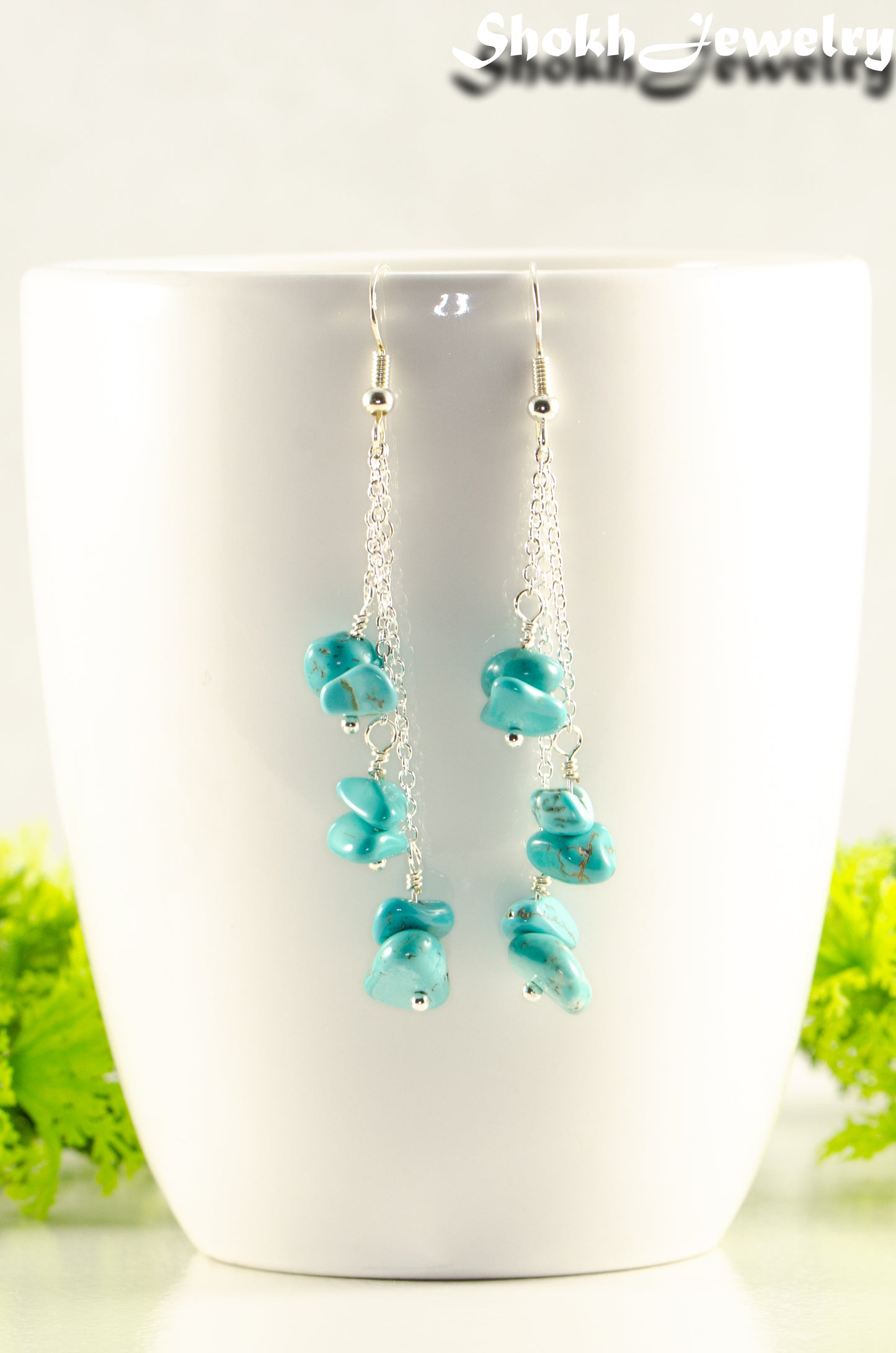 Long Silver Plated Chain and Turquoise Crystal Chip Earrings displayed on a coffee mug.