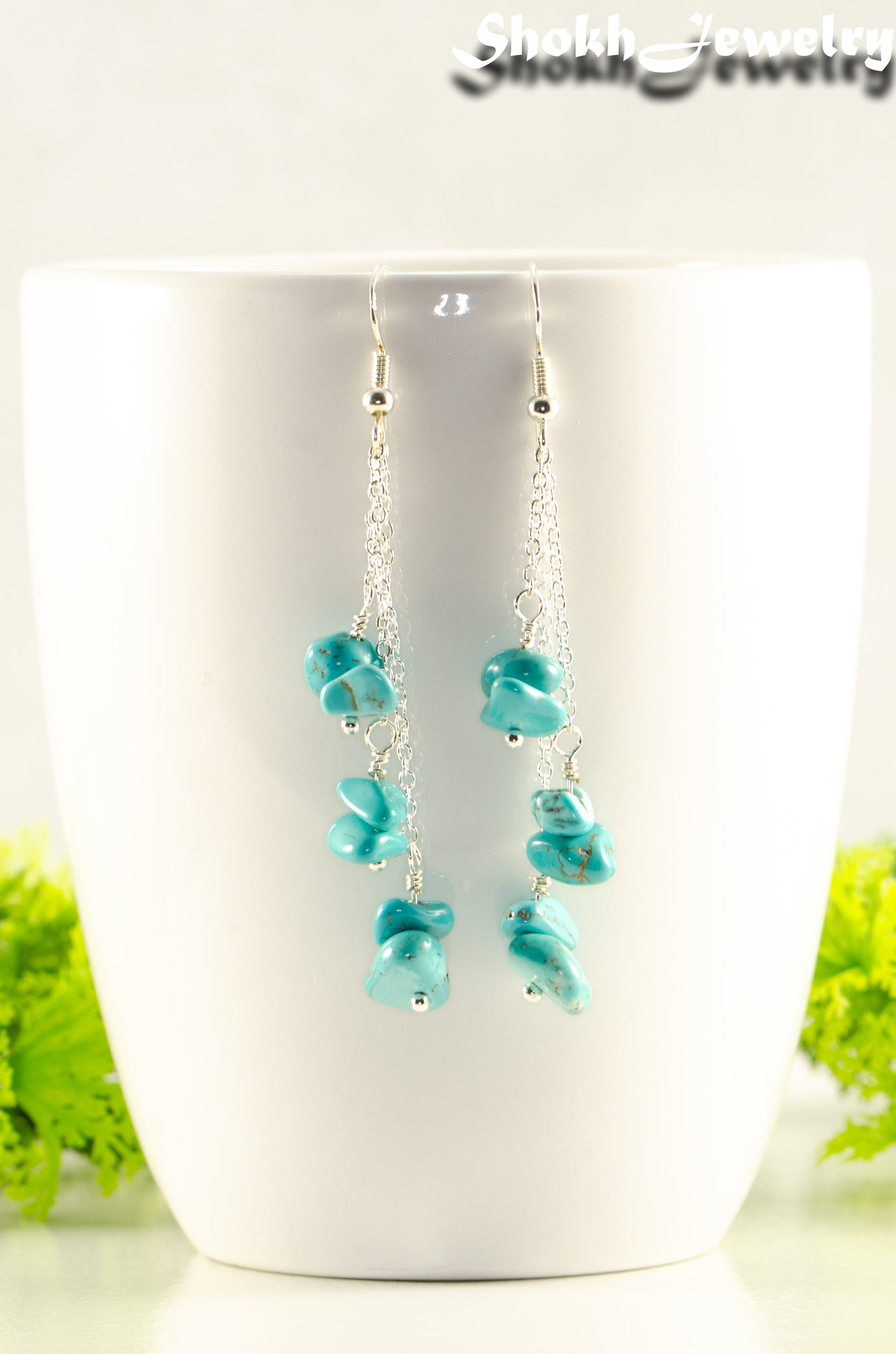 Long Silver Plated Chain and Turquoise Crystal Chip Earrings displayed on a coffee mug.