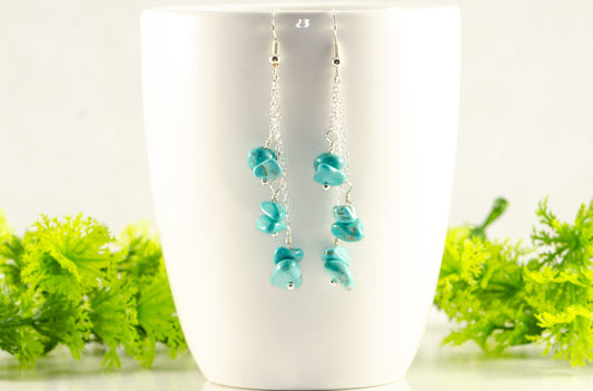 Long Silver Plated Chain and Turquoise Crystal Chip Earrings displayed on a coffee mug.