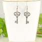 Small Skeleton Key Charm Earrings displayed on a tea cup.