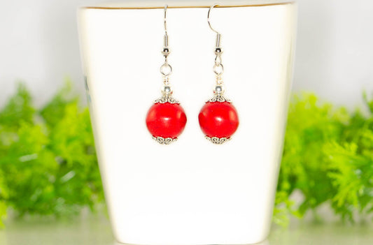 12mm Red Howlite Dangle Earrings displayed on a tea cup.