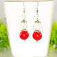 Red and White Howlite Dangle Earrings displayed on a tea cup.