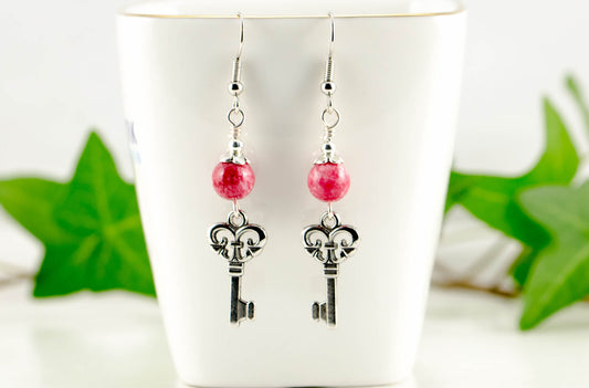 Red Quartzite and Key Charm Dangle Earrings displayed on a tea cup.