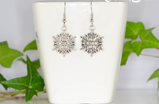 Christmas Snowflakes Charm Earrings displayed on a tea cup.
