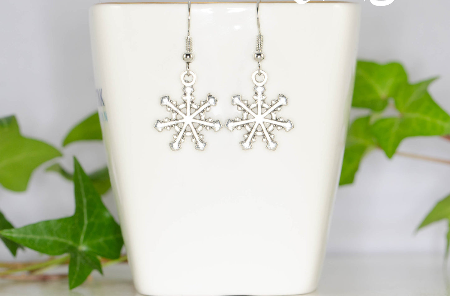 Christmas Snowflakes Charm Earrings displayed on a tea cup.