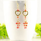 Gold Plated Heart and Red Crystal Cluster Earrings displayed on a coffee mug.