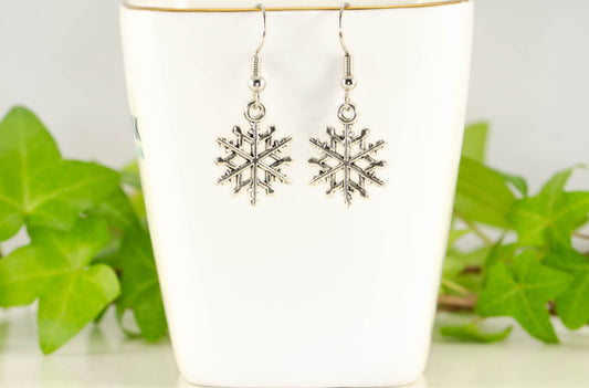 Christmas Snowflakes Charm Earrings displayed on a tea cup.