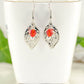 Filigree Silver Leaf Charm and Red Glass Crystal Earrings displayed on a tea cup.