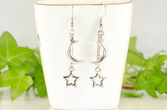 Crescent Moon and Hollow Star Earrings displayed on a tea cup.