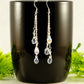 Long Silver Plated Chain and Czech Teardrop Crystal Earrings displayed on a coffee mug.