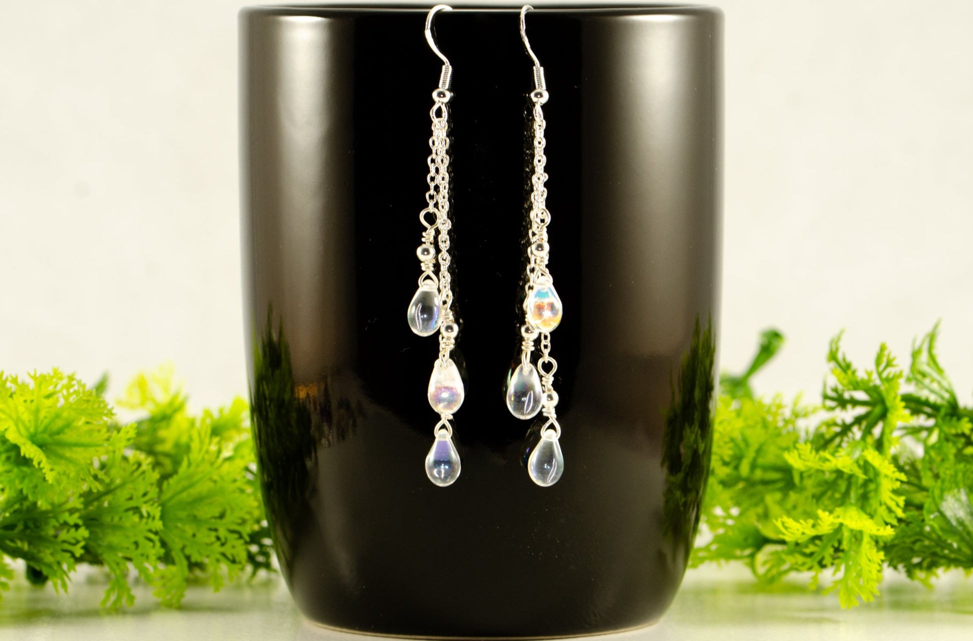 Long Silver Plated Chain and Czech Teardrop Crystal Earrings displayed on a coffee mug.