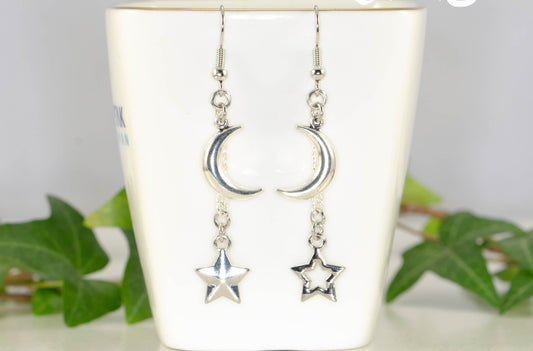 Crescent Moon and Mismatched Star Earrings displayed on a tea cup.