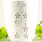 Stainless steel chain and 4 star earrings displayed on a coffee mug.