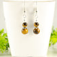 Small Tiger's Eye Earrings displayed on a tea cup.
