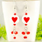 Statement Red Heart Ceramic Bead Earrings displayed on a tea cup.