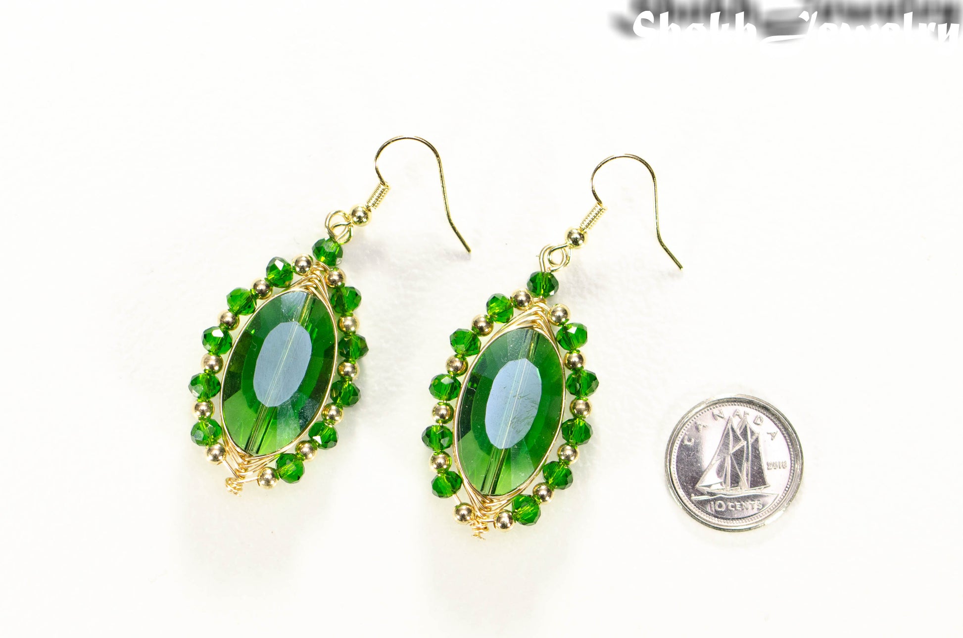 Oval Green Glass Crystal Wire Wrapped Earrings beside a dime.