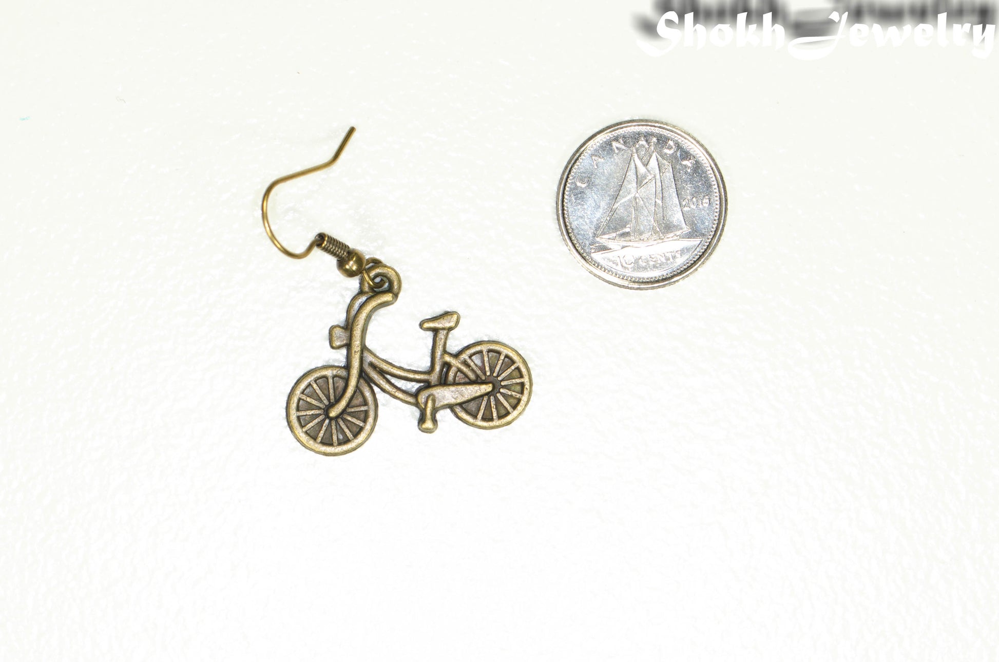 Antique Bronze Bicycle Charm Earrings beside a dime.