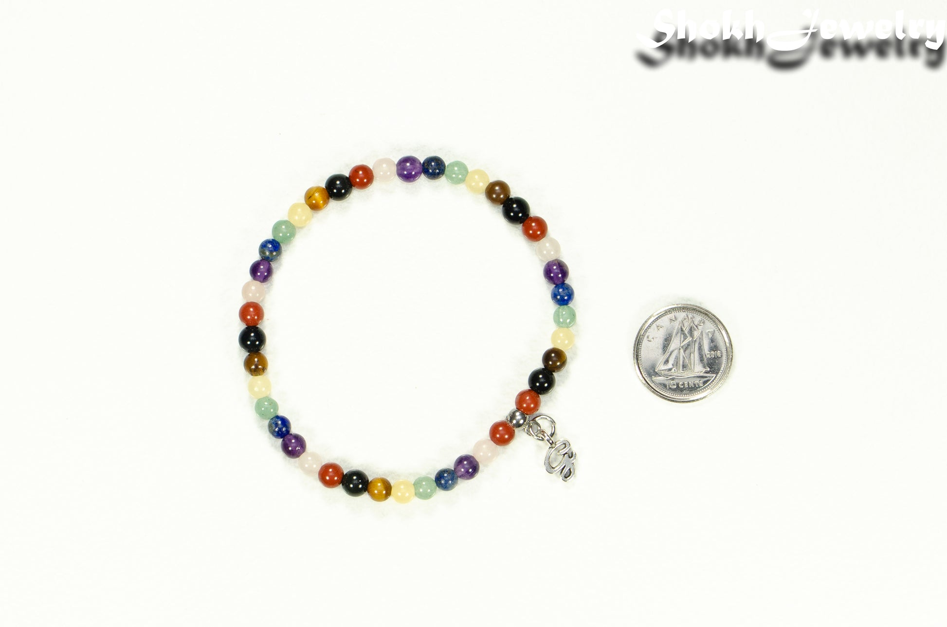 Dainty Gemstone Chakra Bracelet with Initial beside a dime.