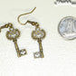Bronze Skeleton Key Charm Earrings beside a dime.