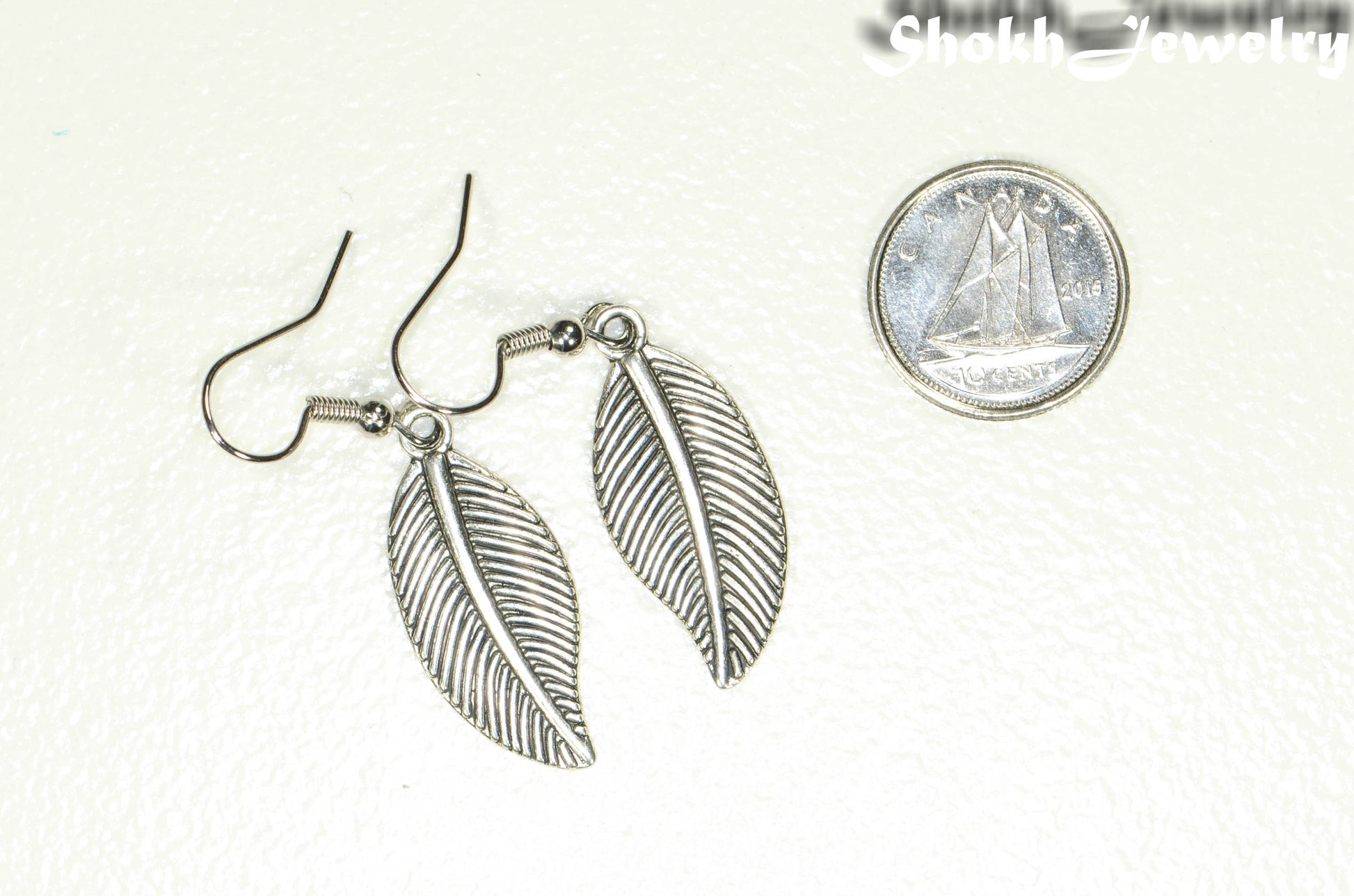 Tibetan Silver Leaf Charm Earrings beside a dime.