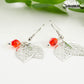 Close up of Filigree Silver Leaf Charm and Red Glass Crystal Earrings.