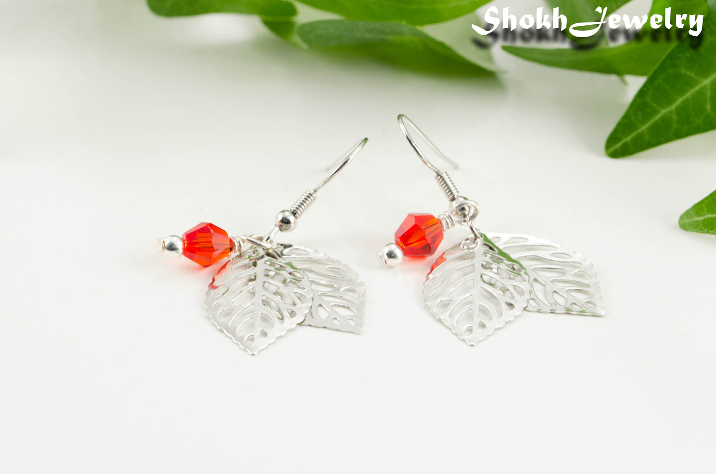 Close up of Filigree Silver Leaf Charm and Red Glass Crystal Earrings.