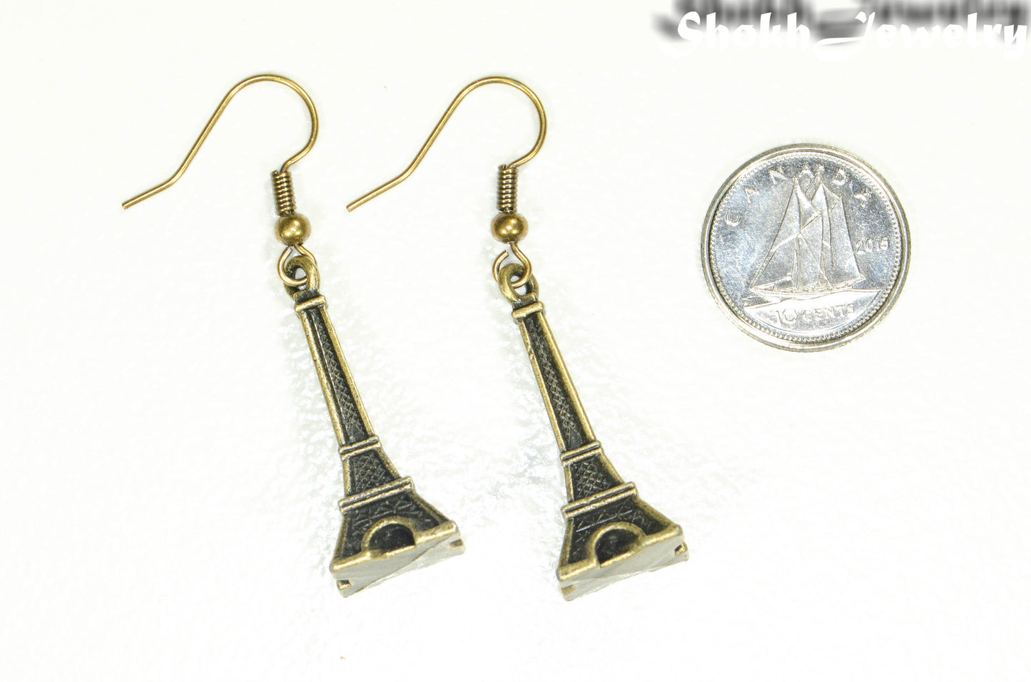 Antique Bronze 3D Eiffel Tower Charm Earrings beside a dime.