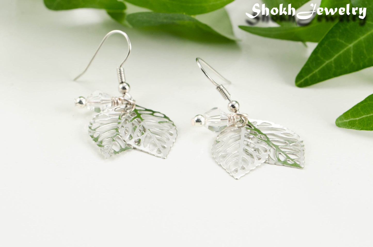 Close up of Filigree Silver Leaf Charm and Clear Glass Crystal Earrings.