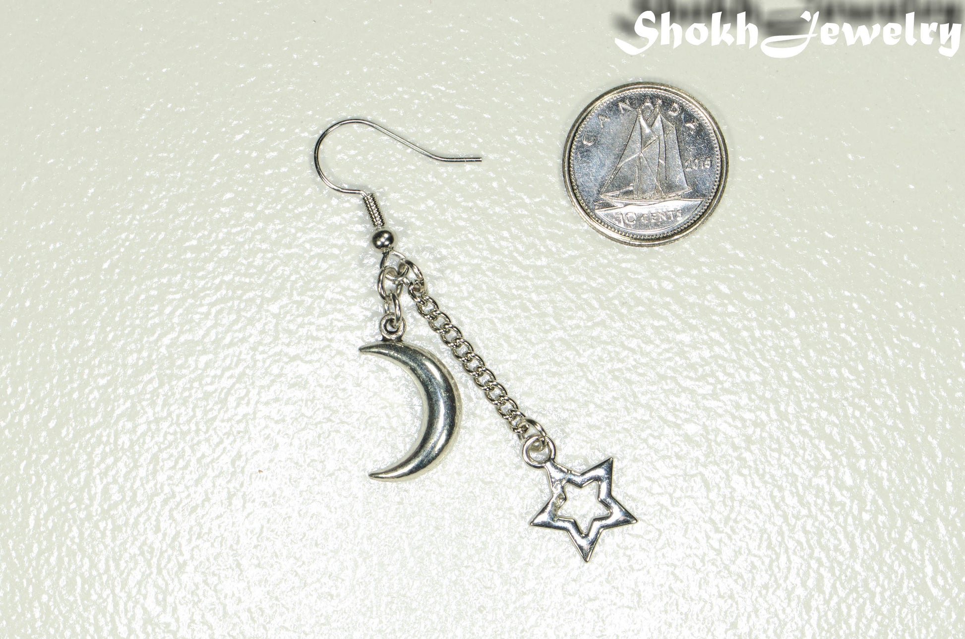 Crescent Moon and Hollow Star Earrings beside a dime.