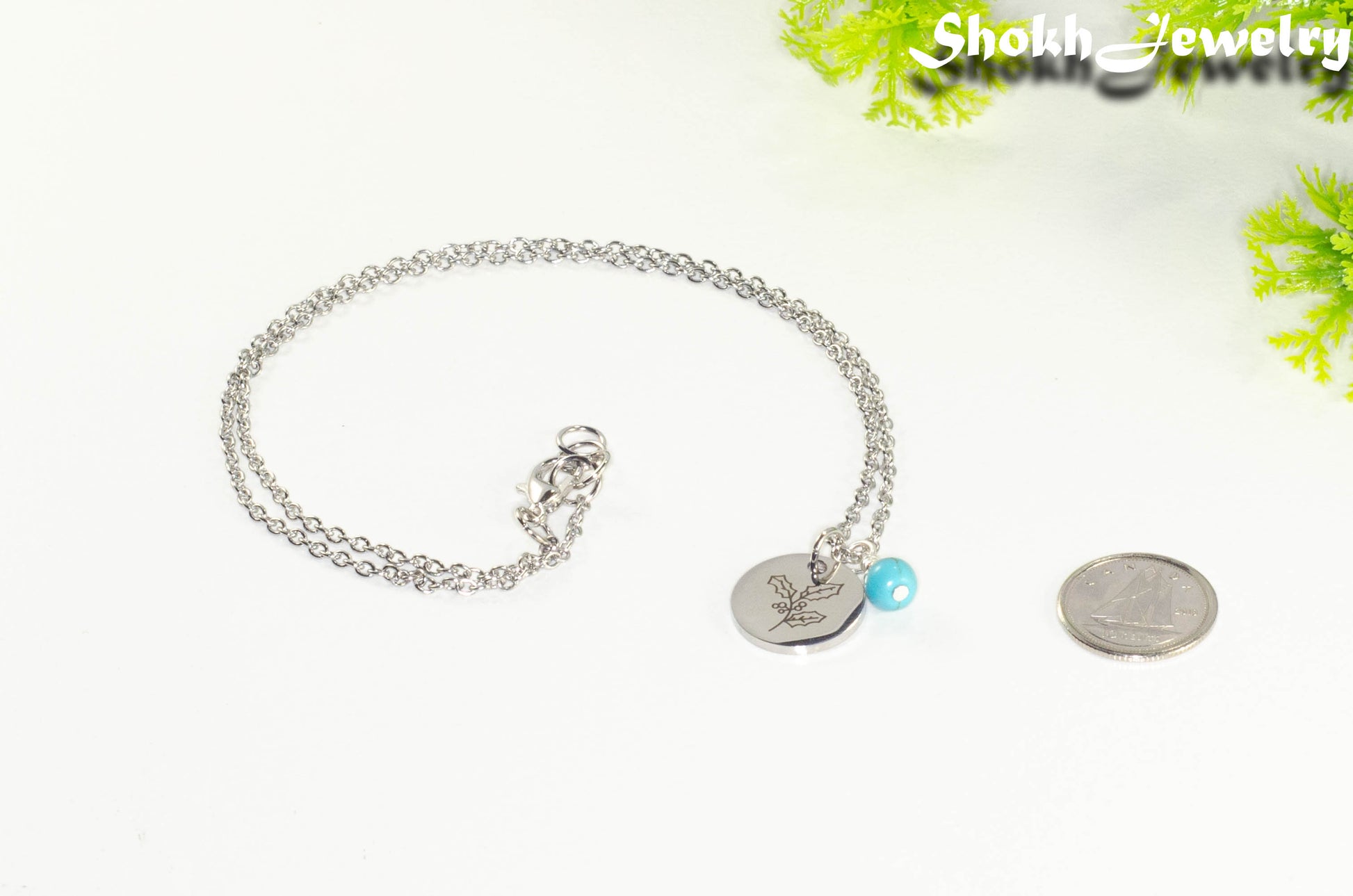 December Birth Flower Necklace with Turquoise Howlite Birthstone Pendant beside a dime.