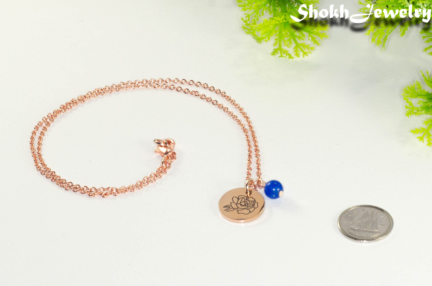 Rose Gold Plated September Birth Flower Necklace with Sapphire Birthstone Pendant beside a dime.