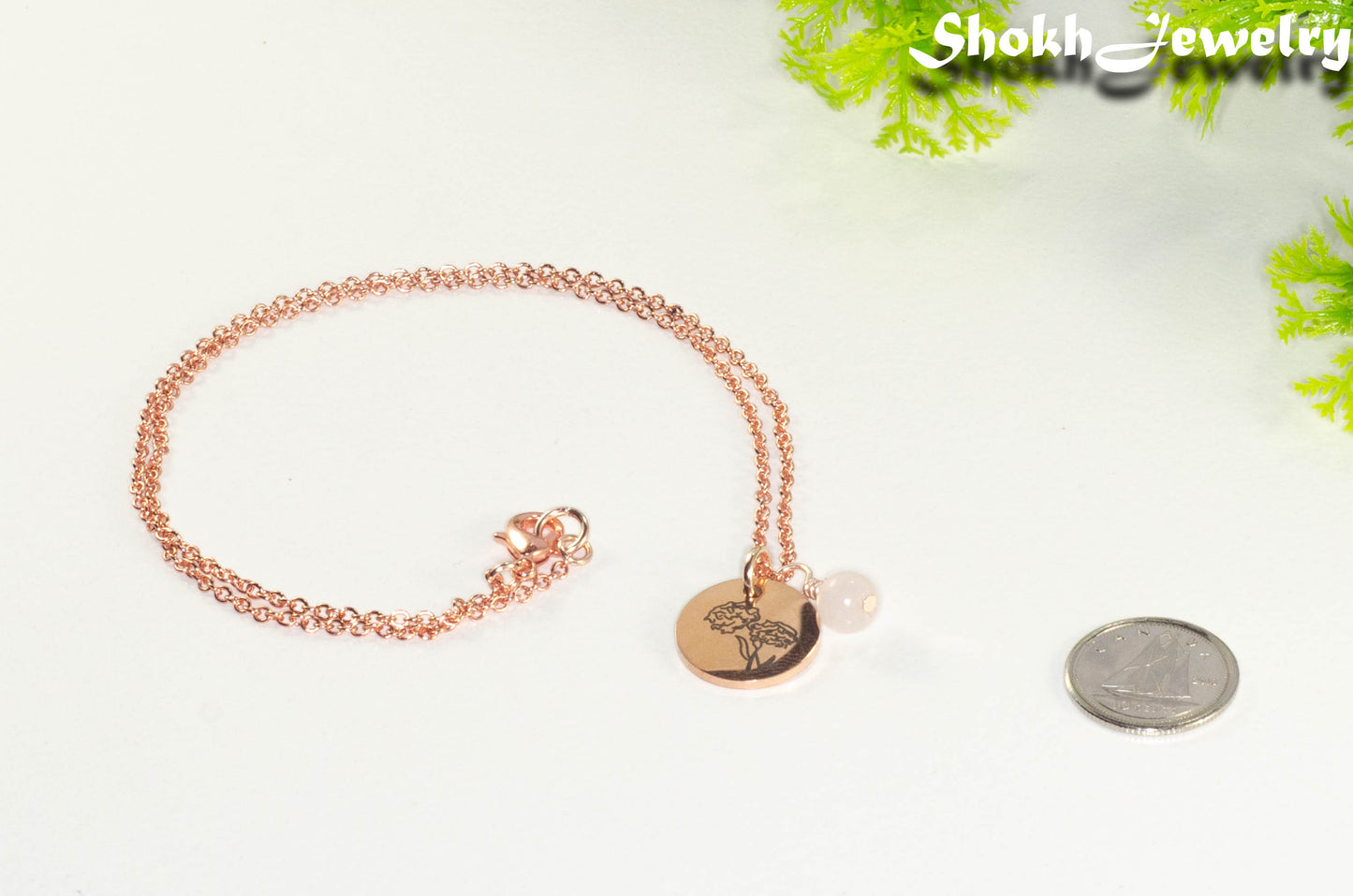 Rose Gold Plated October Birth Flower Necklace with Rose Quartz Birthstone Pendant beside a dime.