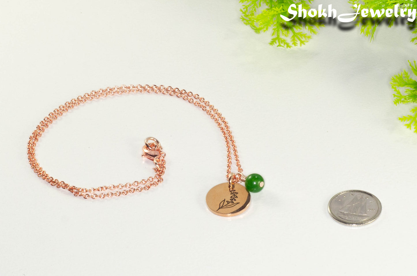 Rose Gold Plated May Birth Flower Necklace with Emerald Birthstone Pendant beside a dime.