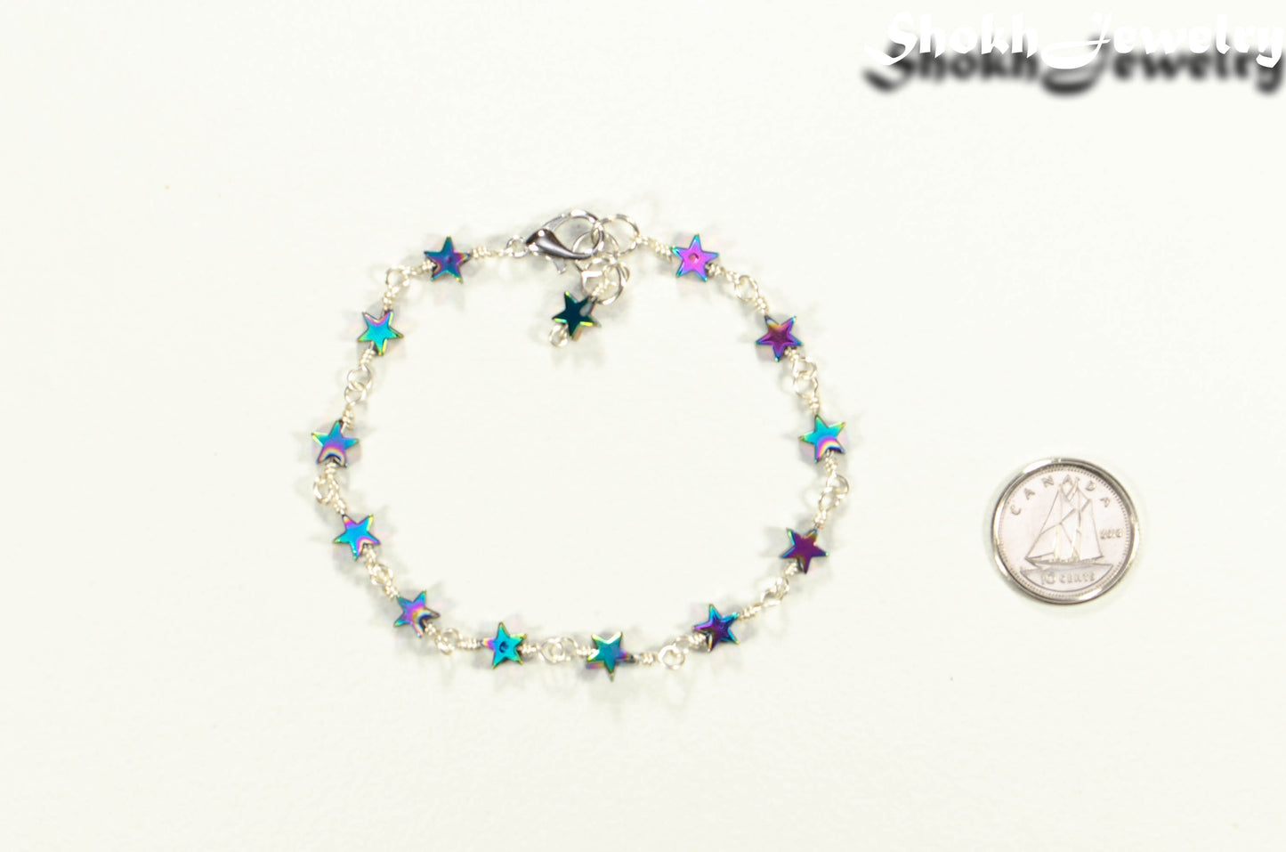 Small Rainbow Hematite Star Link Anklet beside a dime.