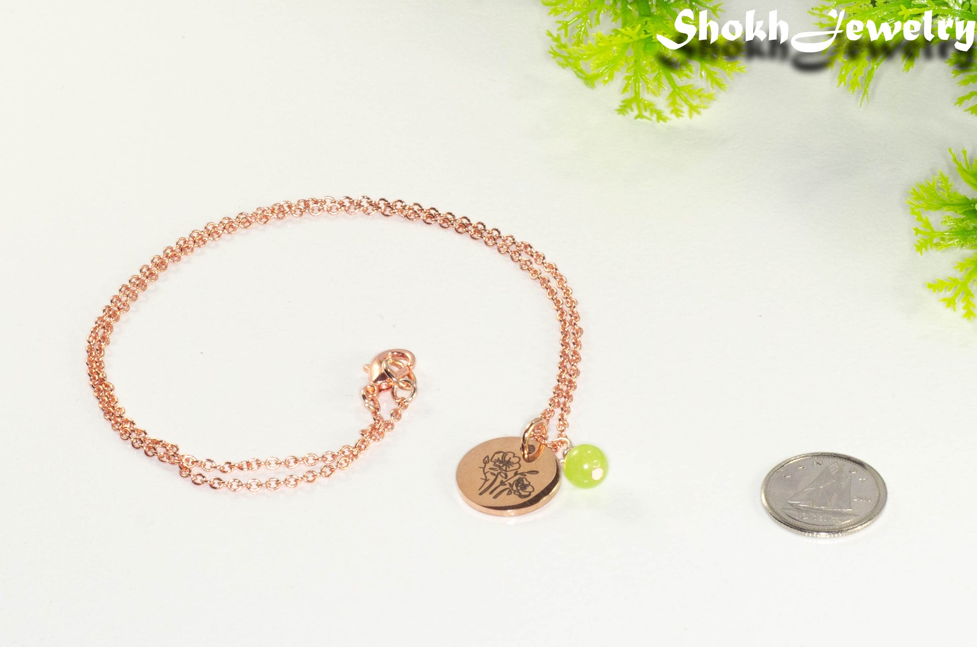 Rose Gold Plated August Birth Flower Necklace with Peridot Birthstone Pendant beside a dime.