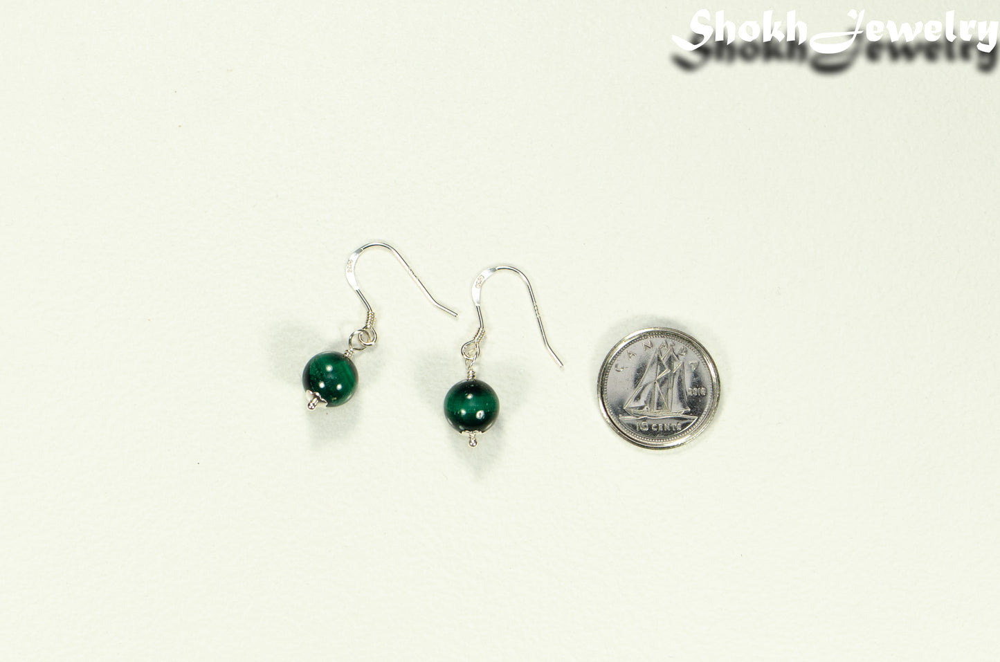 Small Genuine Malachite Drop Earrings beside a dime.