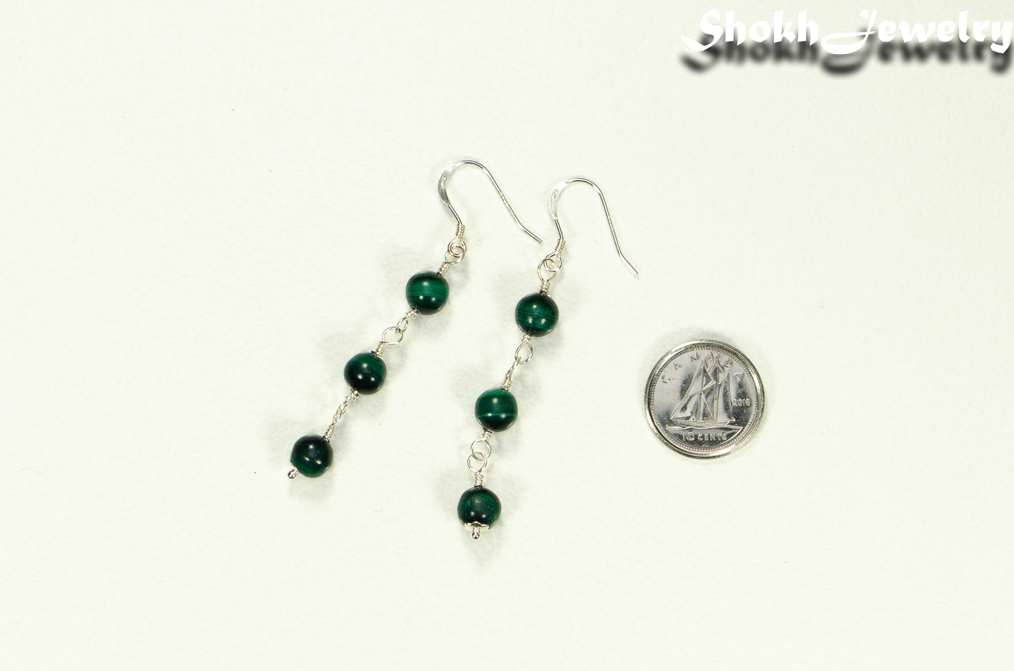 Long Genuine Malachite Dangle Earrings beside a dime.