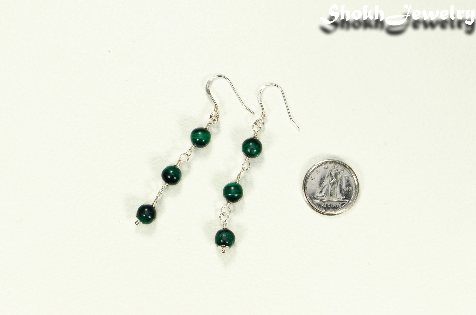 Long Genuine Malachite Dangle Earrings beside a dime.