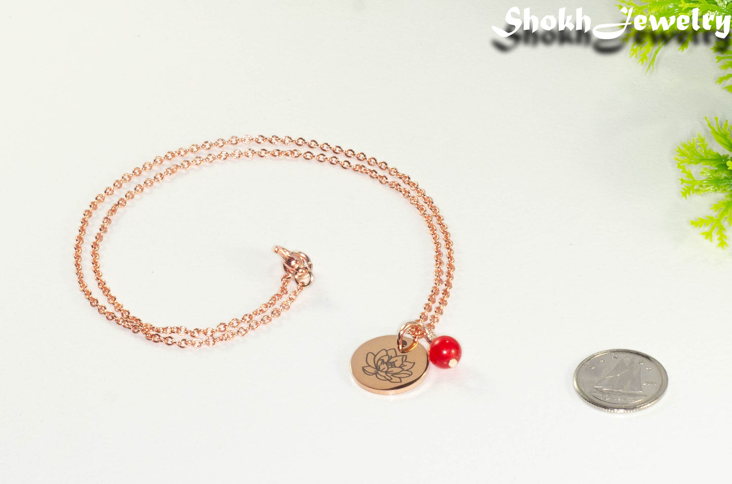 Rose Gold Plated July Birth Flower Necklace with Red Ruby Birthstone Pendant beside a dime.
